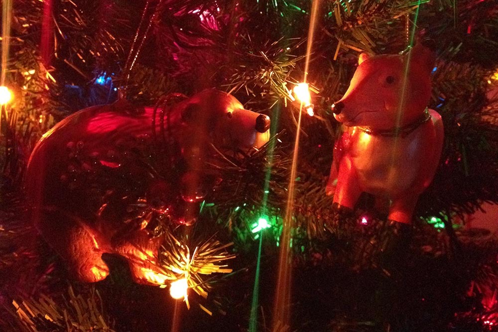 A bear and fox ornament on a multi-color lit up Christmas tree.